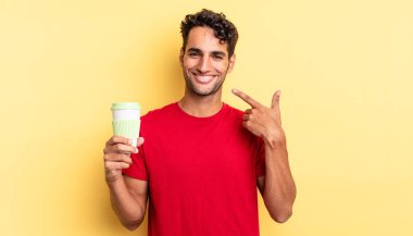 İspanyol yakışıklı adam kendine güvenerek gülüyor ve kendi gülüşüne işaret ediyor. kahve konseptini kaldır.
