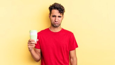 Hispanik yakışıklı adam üzgün ve mızmız, mutsuz bir bakışla ağlıyor. kahve konseptini kaldır.