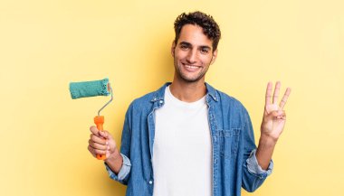 İspanyol yakışıklı adam gülümsüyor ve arkadaş canlısı görünüyor, üç numarayı gösteriyor. paten boya kavramı