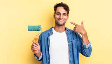 İspanyol yakışıklı adam kendine güvenerek gülüyor ve kendi gülüşüne işaret ediyor. paten boya kavramı