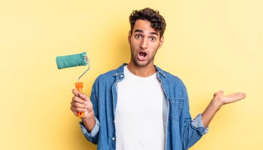 İspanyol yakışıklı adam şaşırmış ve şok olmuş görünüyor. Çenesi düşmüş ve elinde bir nesne var. paten boya kavramı