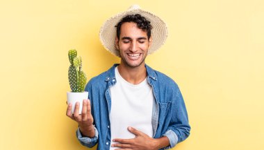 İspanyol yakışıklı bir adam komik bir şaka çiftçisi ve kaktüs kavramına yüksek sesle gülüyor.