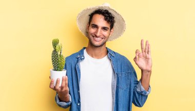 İspanyol yakışıklı adam kendini mutlu hissediyor, iyi bir jest çiftçisi ve kaktüs konseptiyle onaylıyor.