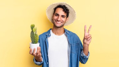İspanyol yakışıklı gülümseyen ve mutlu görünen, zafer işareti yapan ya da barış yanlısı çiftçi ve kaktüs kavramı