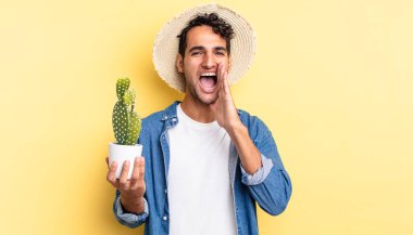 İspanyol yakışıklı adam kendini mutlu hissediyor, elleri ağızda çiftçi ve kaktüs kavramının yanında bağırıyor.