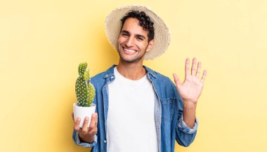 İspanyol yakışıklı adam mutlu bir şekilde gülümsüyor, el sallıyor, hoşgeldin diyor ve seni selamlıyor çiftçi ve kaktüs kavramı