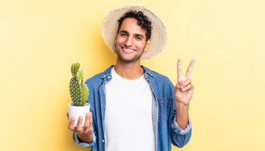İspanyol yakışıklı adam gülümsüyor ve arkadaş canlısı görünüyor. İki numaralı çiftçi ve kaktüs kavramını gösteriyor.