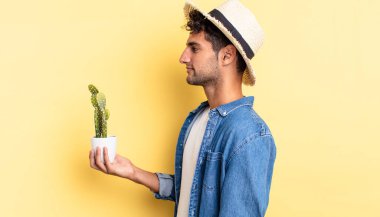 Profil görünümlü İspanyol yakışıklı adam hayal ediyor, hayal ediyor ya da hayal kuruyor çiftçi ve kaktüs kavramı