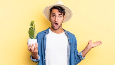 İspanyol yakışıklı adam şaşırmış ve şok olmuş görünüyor, çenesi düşmüş, elinde bir nesne çiftçisi ve kaktüs kavramı tutuyordu.
