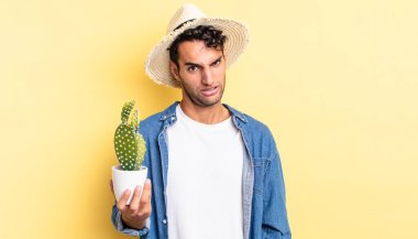 Hispanik yakışıklı adam şaşkın ve kafası karışmış çiftçi ve kaktüs kavramı