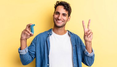 İspanyol yakışıklı adam gülümsüyor ve mutlu görünüyor, zafer ya da barış işareti yapıyor. astım konsepti