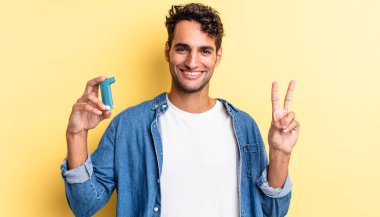 İspanyol yakışıklı adam gülümsüyor ve arkadaş canlısı görünüyor, iki numarayı gösteriyor. astım konsepti