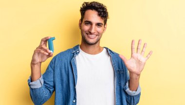 İspanyol yakışıklı adam gülümsüyor ve arkadaş canlısı görünüyor, beş numarayı gösteriyor. astım konsepti