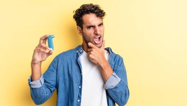 Ağzı ve gözleri açık, eli çenesinde İspanyol yakışıklı bir adam. astım konsepti