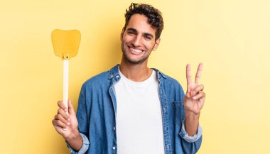 İspanyol yakışıklı adam gülümsüyor ve mutlu görünüyor, zafer ya da barış işareti yapıyor. Sinekleri öldürür