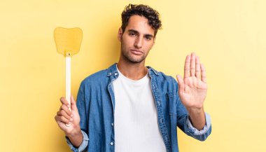 İspanyol yakışıklı adam ciddi görünüyor. Avuç içi gösteriyor. Durdurma hareketi yapıyor. Sinekleri öldürür