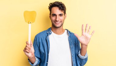 İspanyol yakışıklı adam gülümsüyor ve arkadaş canlısı görünüyor, beş numarayı gösteriyor. Sinekleri öldürür