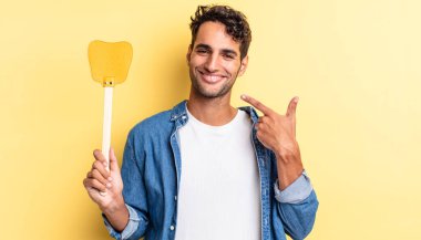 İspanyol yakışıklı adam kendine güvenerek gülüyor ve kendi gülüşüne işaret ediyor. Sinekleri öldürür