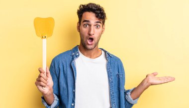 İspanyol yakışıklı adam şaşırmış ve şok olmuş görünüyor. Çenesi düşmüş ve elinde bir nesne var. Sinekleri öldürür