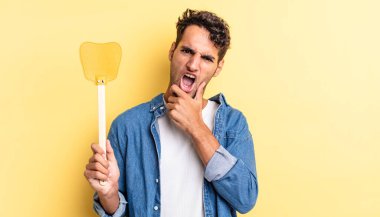 Ağzı ve gözleri açık, eli çenesinde İspanyol yakışıklı bir adam. Sinekleri öldürür