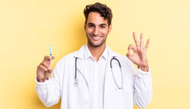 İspanyol yakışıklı adam kendini mutlu hissediyor, iyi bir jest doktoru ve srynge konseptiyle onaylıyor.