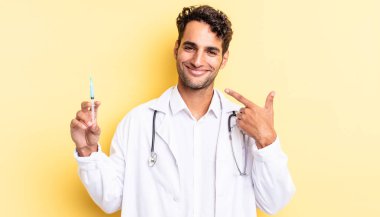 İspanyol yakışıklı adam kendine güvenerek gülümsüyor. Kendi gülümseyen doktor ve doktor konseptine işaret ediyor.