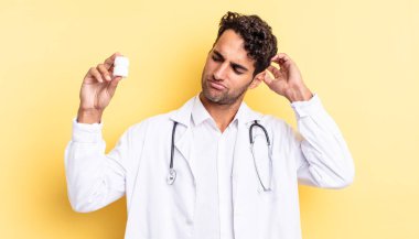 İspanyol yakışıklı adam şaşkın ve kafası karışık, kaşınan bir kafa hissediyor. Hekim şişesi hapları konsepti