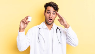 İspanyol yakışıklı adam mutlu, şaşkın ve şaşırmış görünüyor. Hekim şişesi hapları konsepti