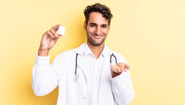 İspanyol yakışıklı adam mutlu bir şekilde gülümsüyor ve bir konsept sunuyor. Hekim şişesi hapları konsepti