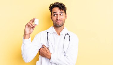 İspanyol yakışıklı adam omuz silkiyor, kafası karışık ve kararsız. Hekim şişesi hapları konsepti