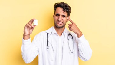 İspanyol yakışıklı adam kafası karışık ve şaşkın hissediyor, senin deli olduğunu gösteriyor. Hekim şişesi hapları konsepti