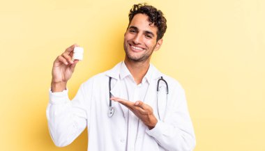 İspanyol yakışıklı adam neşeyle gülümsüyor, mutlu hissediyor ve bir konsept gösteriyor. Hekim şişesi hapları konsepti