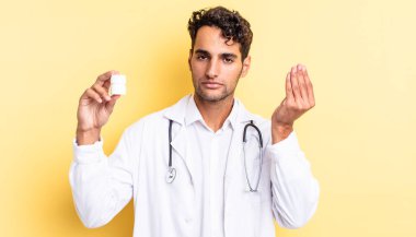 İspanyol yakışıklı adam kapiş ya da para hareketi yapıyor, sana ödemeni söylüyor. Hekim şişesi hapları konsepti