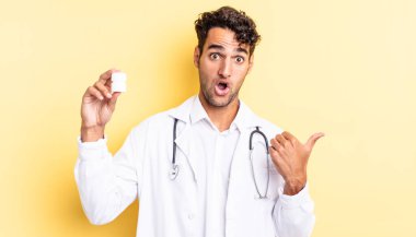 İspanyol yakışıklı adam, inançsızlıktan şaşkın şaşkın bakıyor. Hekim şişesi hapları konsepti