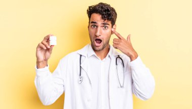 İspanyol yakışıklı adam şaşırmış görünüyor, yeni bir düşünce, fikir ya da konsept fark ediyor. Hekim şişesi hapları konsepti