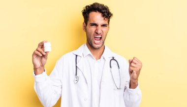 İspanyol yakışıklı adam sinirli bir ifadeyle agresif bir şekilde bağırıyor. Hekim şişesi hapları konsepti