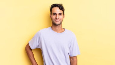 İspanyol yakışıklı adam mutlu bir şekilde gülümsüyor elleri kalçasında ve kendinden emin