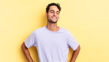 İspanyol yakışıklı adam mutlu görünüyor ve iki elini de kalçasında istiyor.