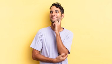 İspanyol yakışıklı adam mutlu bir şekilde gülümsüyor ve hayal kuruyor ya da şüphe ediyor.