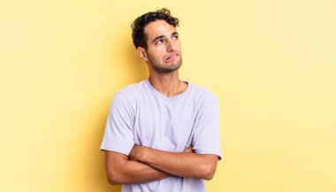 Hispanik yakışıklı adam şüpheleniyor ya da düşünüyor, dudağını ısırıyor ve güvensiz hissediyor.