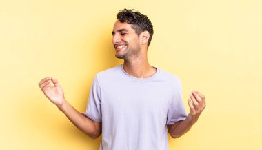İspanyol yakışıklı adam gülümsüyor, kaygısız hissediyor ve dans ediyor ve müzik dinliyor.
