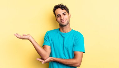 Hispanik yakışıklı adam gururla ve özgüvenle gülümsüyor, mutlu ve tatmin olmuş hissediyor.