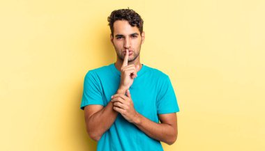 İspanyol yakışıklı adam ciddi görünüyor ve sessizlik talep ediyor, sır saklıyor.