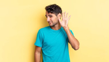 İspanyol yakışıklı adam gülümsüyor, tuhaf bir şekilde yana bakıyor, dinlemeye çalışıyor.