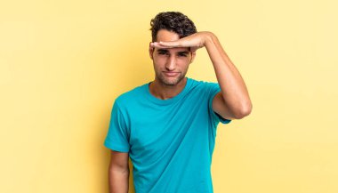 İspanyol yakışıklı adam bakıyor ve şaşkına dönmüş, alnının üzerinde uzaklara bakıyor.