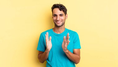 İspanyol yakışıklı adam mutlu ve başarılı hissediyor, gülümsüyor ve alkışlıyor.