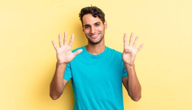 İspanyol yakışıklı adam gülümsüyor ve arkadaş canlısı görünüyor, dokuz numarayı gösteriyor.