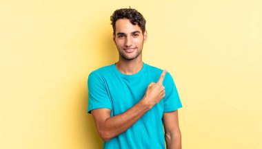 İspanyol yakışıklı adam neşeyle gülümsüyor, mutlu hissediyor ve bir tarafa işaret ediyor.