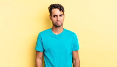 Hispanik yakışıklı adam üzgün, üzgün ya da kızgın hissediyor ve yana bakıyor.