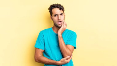 İspanyol yakışıklı adam şok ve inançsızlıkla ağzı açık, elleri yanağında.